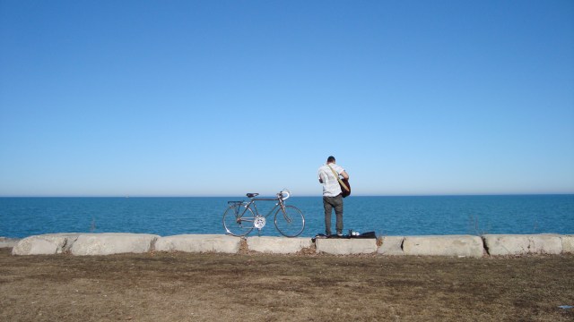 A lone guitarist playing to lake Michigan